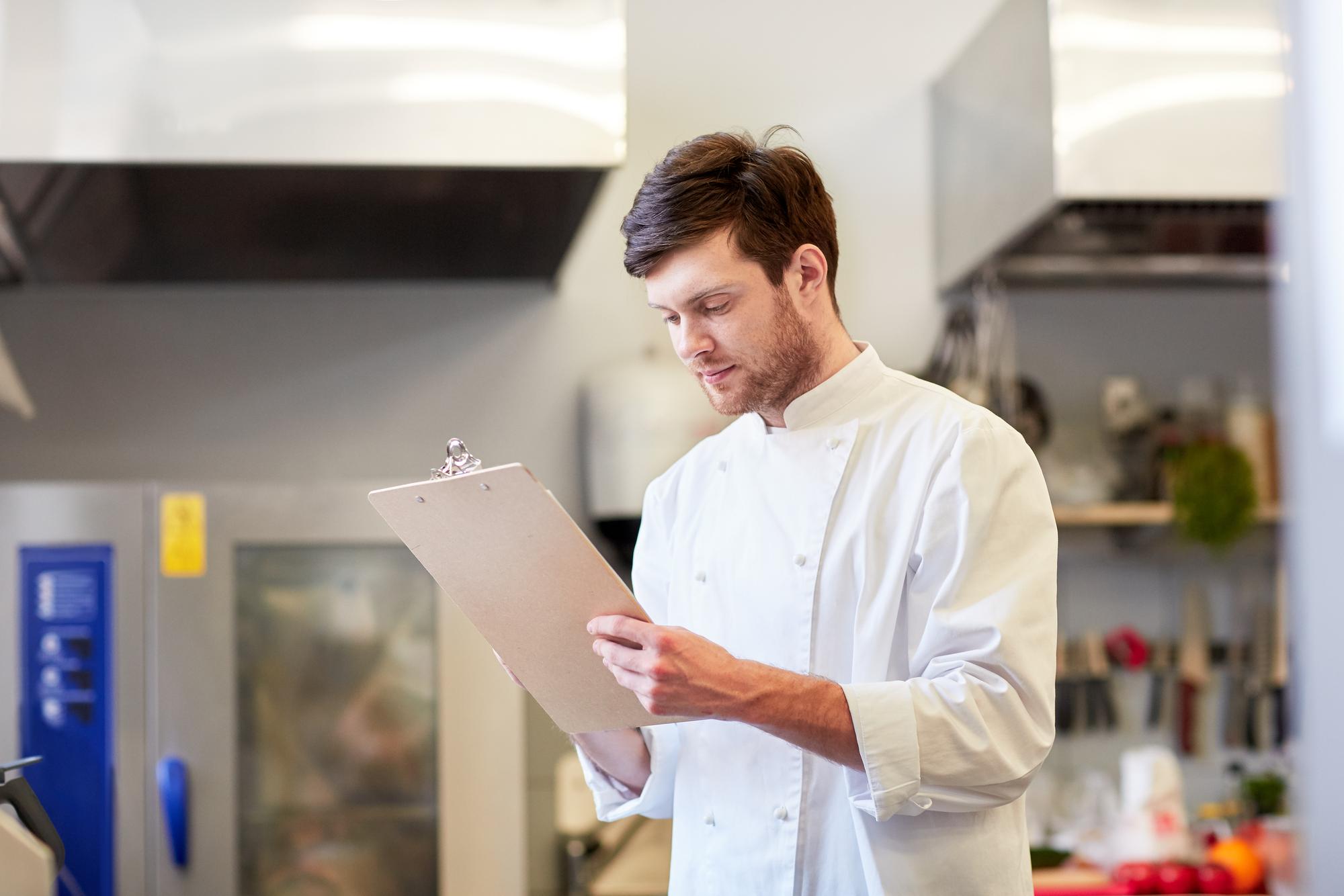 kitchen technician reviewing production checklist